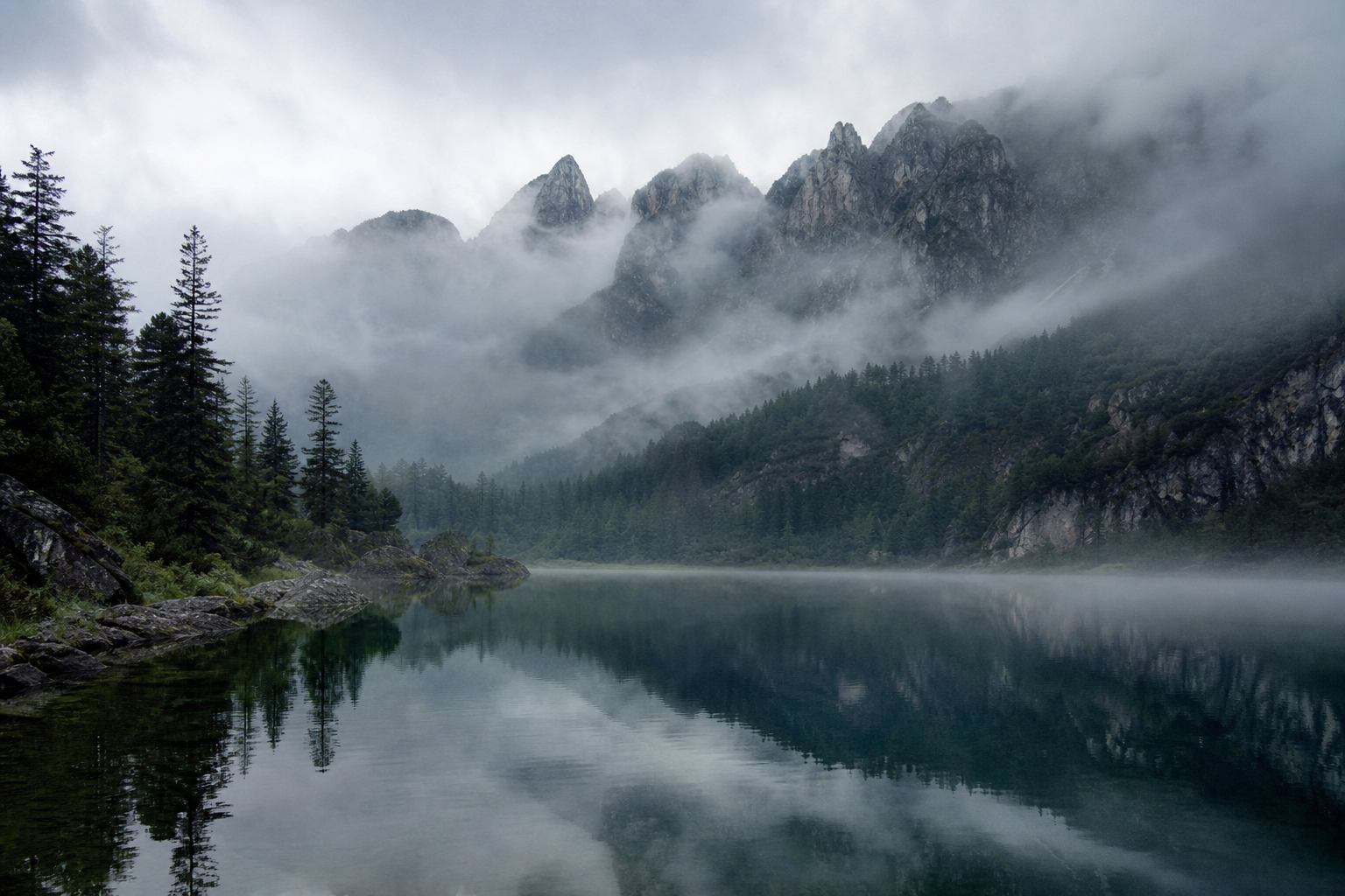 Morgennebel über einem alpinen See in den Bayerischen Alpen mit spiegelnder Wasseroberfläche
